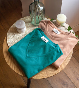Tshirt d'allaitement sable et vert émeraude disposés sur une table basse